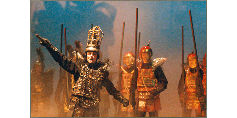 A production image of John Bell and cast in ‘Richard III’, showing an army carrying spears being exhorted ahead by a passionate Richard III.