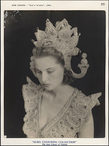 An old sepia-toned trading card, yellowing with age, showing a woman wearing an ornate Asian-inspired headdress and costume. She is looking down, out of frame.