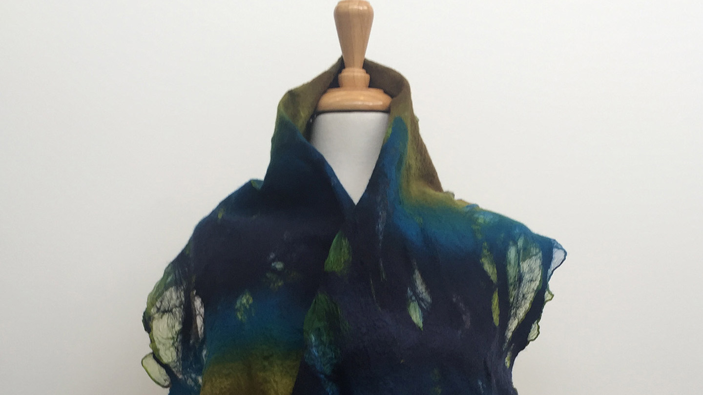 A flowing scarf in dark ocean tones wrapped around a mannequin