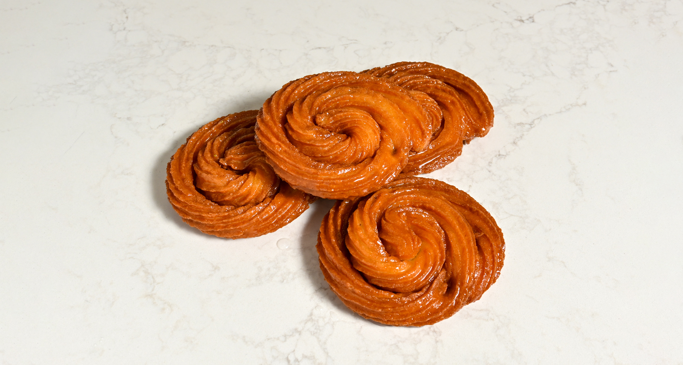 A flat lay style image of a stack of four Turkish donuts that are in a spiral shape. 