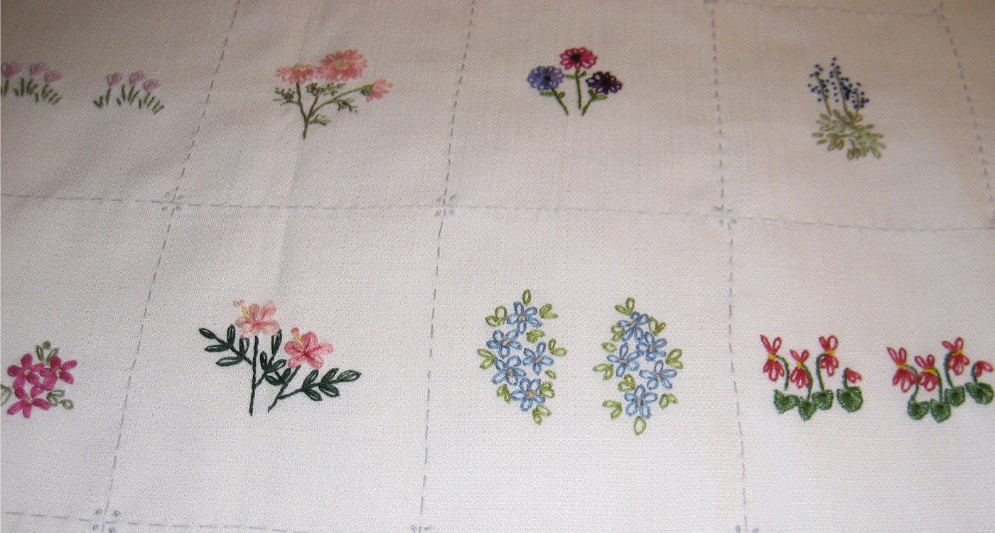 A top down image of flower embroidery on a white cloth. 