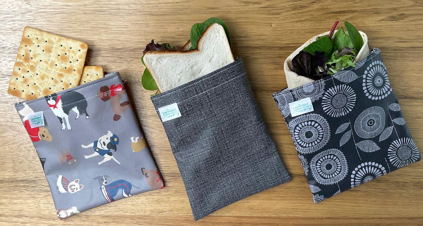 A top down image of three patterned pouches with crackers, a sandwich and a wrap coming out the top. 