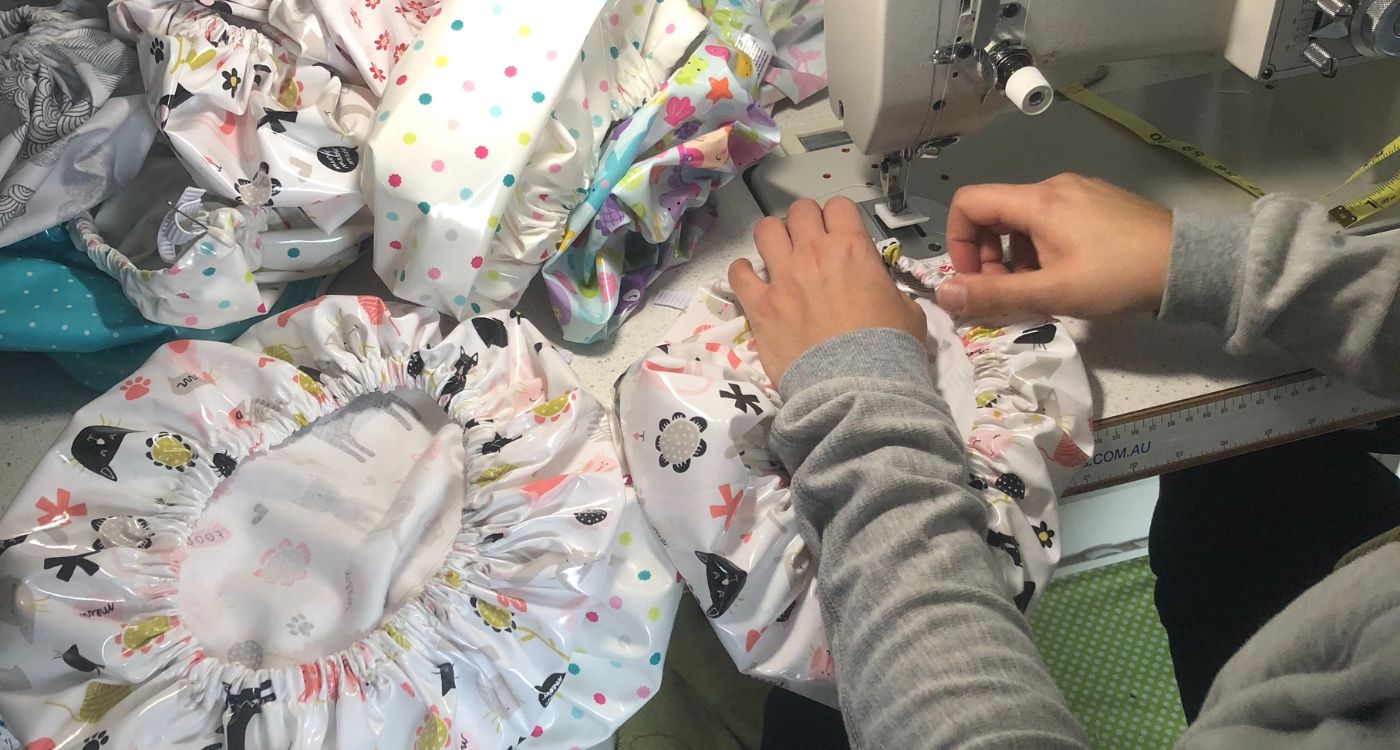 A top down image of a person using a sewing machine to make a shower cap. 